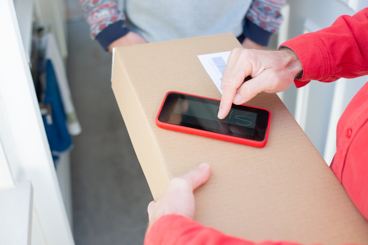 A person signs a package delivery confirmation using a smartphone, showcasing contact-free delivery.